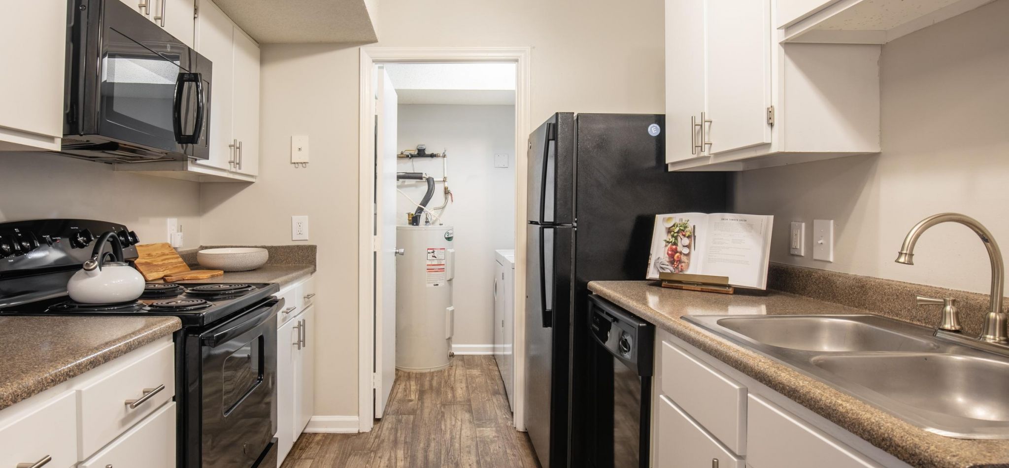 Hawthorne Commons apartment kitchen interior with wood vinyl flooring, sleek black energy efficient appliances, and designer cabinetry